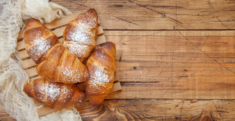 French fresh crusty croissants on a wooden table top view