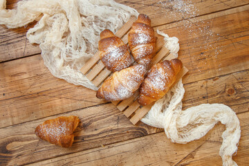 French fresh crusty croissants on a wooden table top view
