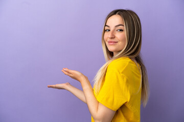 Young woman over isolated purple background extending hands to the side for inviting to come