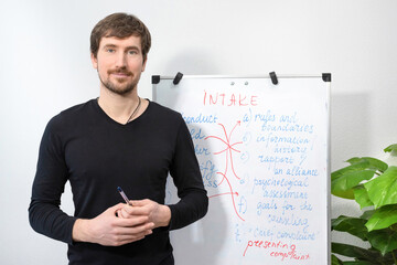 Male English teacher holds an online lesson with students. A young teacher presents a new topic on flip chart. Online training, education concept