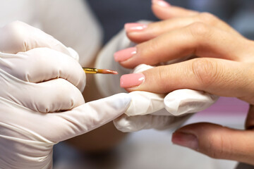 Obraz na płótnie Canvas Manicure coating and strengthening of natural nails with artificial material gel in a beauty salon by a specialist. Close-up. Space for text 