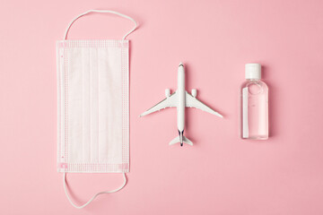 Above mask airplane and sanitizer antiseptic isolated on the pink background with empty space