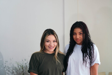 Portrait of two friends laughing looking at the camera on a white background. Two friends at home.