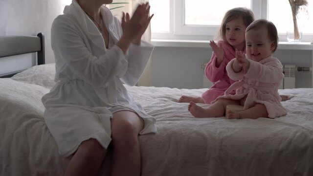 happy united family applaud health workers, doctors and heroes in fight against coronavirus pandemic. mom and kids in bathrobes after bath on bed oposite window. Celebration quarantine ending concept