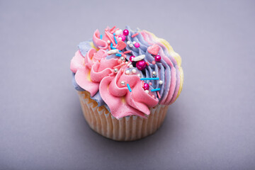 Close up of multicolored creamy cupcake with decorations with colorful stars, delicious and fabulous. Top view on gray background. Concept of birthday, celebration, sweet.
