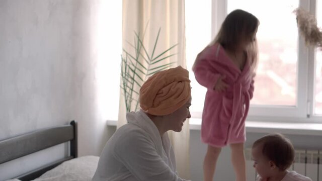 happy united family applaud health workers, doctors and heroes in fight against coronavirus pandemic. mom and kids in bathrobes after bath on bed oposite window. Celebration quarantine ending concept