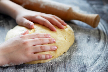 Hands, rolling-pin and dough for bread, pasta or pizza on wooden table