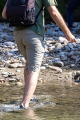 A young man taking a walk on a river, in shallow water, on a sunny day, forcing it into a ford.