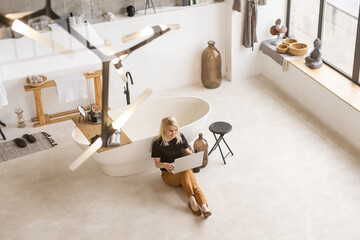 Happy casual beautiful woman working on a laptop sitting in the house.
