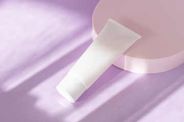 Skin care cosmetic bottle mockup on lilac podium. Facial cream, moisturizer, lotion jar plastic tube on background with natural shadows, high angle view. Brand spa packaging mock up. Branding identity