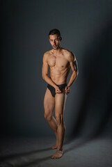 Naklejka premium Sexy man with a muscular body posing naked with black underpants inside a studio