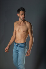 Studio portrait of a shirtless sexy man with abs in denim blue jeans