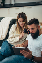 Couple using a digital tablet and a smartphone at home
