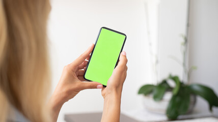 Hands of young woman hold phone with green screen. Girl talking online with her mother and friends. Person study new technology,  work online, communication.