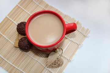 Coffee with milk and a smile in a cup. Heart made from coffee beans on a wooden table.