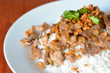 Thai garlic pork with rice on a white plate. 