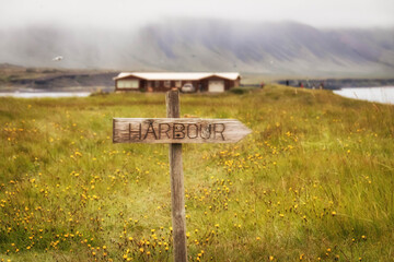 Iceland field and mountains in mist with sign to harbor