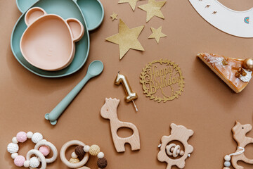 One year baby concept. Top view composition with newborn accessories, birthday cake, wooden toys on brow background.