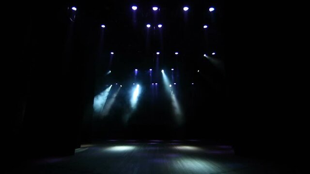 Many lighting devices strobing on the empty stage of the concert hall.