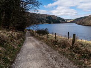 View of a part of the water reservoir and the path surrounded by forests, hills, greenery at the beginning of spring.