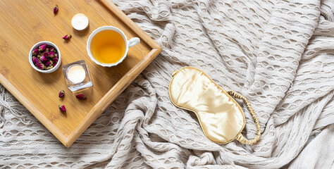 Cozy home interior with warm blanket. herbal tea, aromatic candles and rose buds. Hygge style...