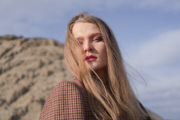 Fototapeta premium Beauty portrait of a young blond girl in a vintage dress. She is posing on a sandy landscape.