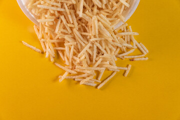 White bowl with potato straw on yellow background