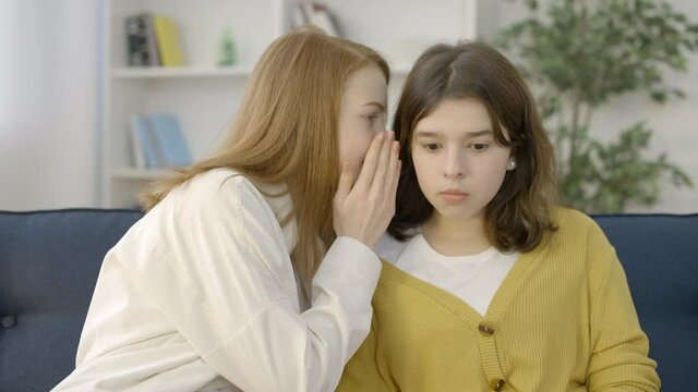 Teenage girl telling big secret to her surprised female friend, friendship