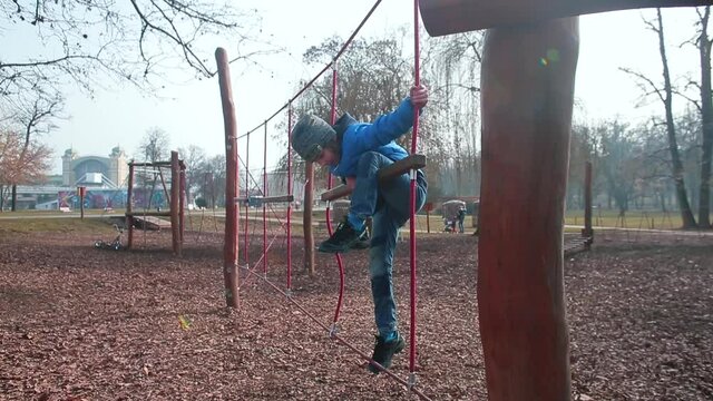 Climb the ropes. Balance training. The child plays in the playground. He's climbing ropes, coordination training.
