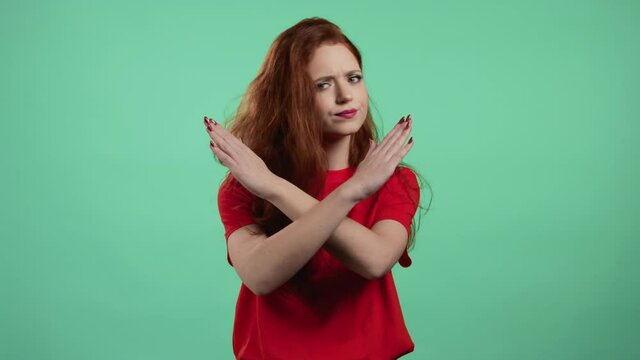Pretty girl disapproving with no crossing hands sign make basta, negation, enough gesture. Denying, Rejecting, Disagree, Portrait of pretty girl on green background