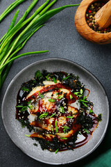 baked eel with rice and green onion on dark background closeup