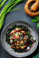 baked eel with rice and green onion on dark background closeup