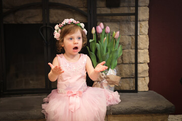 Close Up Portrait, 2 Years Old Toddler Girl with Big Blue Eyes, in light Pink Dress with Pink Flowers on her head, Sitting by the fireplace, Birthday Girl, Ukrainian Head bend, Little Princess 
