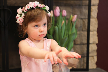 Close Up Portrait, 2 Years Old Toddler Girl with Big Blue Eyes, in light Pink Dress with Pink Flowers on her head, Sitting by the fireplace, Birthday Girl, Ukrainian Head bend, Little Princess 