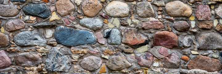 Ancient stone wall. Weathered rough masonry surface. The wall of the old castle. Wide panoramic texture for background and design.