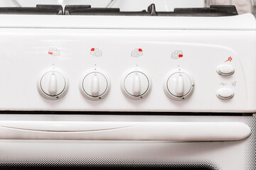Frontal view of a white gas stove with burner control buttons, close up
