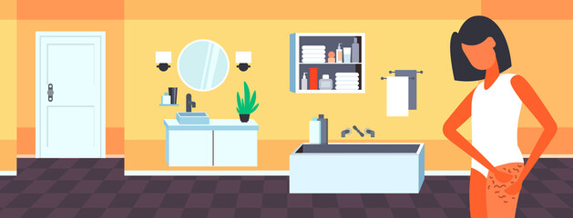 woman testing skin presence of stretch marks checking cellulite on her buttock girl clamping fat fold on hip diet weight loss concept bathroom interior portrait horizontal