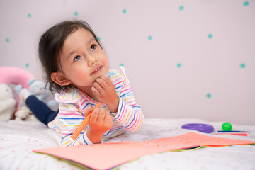 Young child looks thoughtful while drawing.