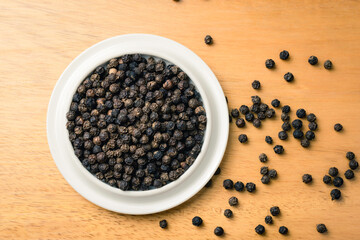 Black pepper seeds in a cup on the table, spices used in cooking