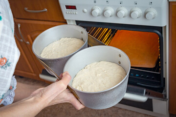 The woman puts the forms with dough in the oven, will bake yeast-free bread.