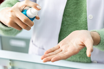 Closeup of Asian Medical Personnel hand holding Spray for wash hand sanitizer before work for Protect herself and her patients  from COVID19. 