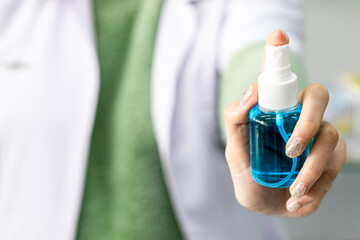 Closeup of Asian Medical Personnel hand holding Spray for wash hand sanitizer before work for Protect herself and her patients  from COVID19. 
