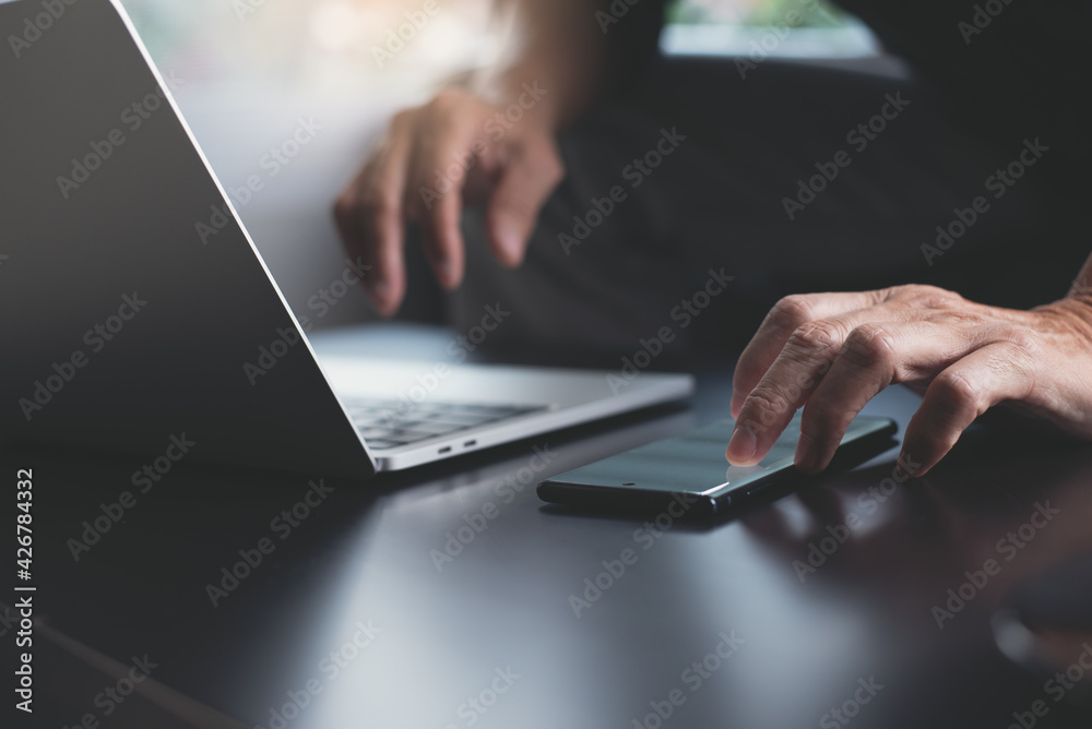 Poster man busy working on laptop computer and using mobile phone surfing the internet on table