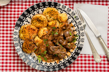 Beef kidney, leek and onion stew with Spanish style potatoes served on a vintage plate.