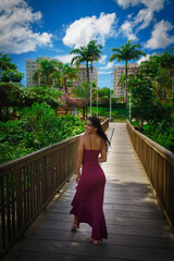 Woman on her back walking on wooden bridge, holding red flower in spring