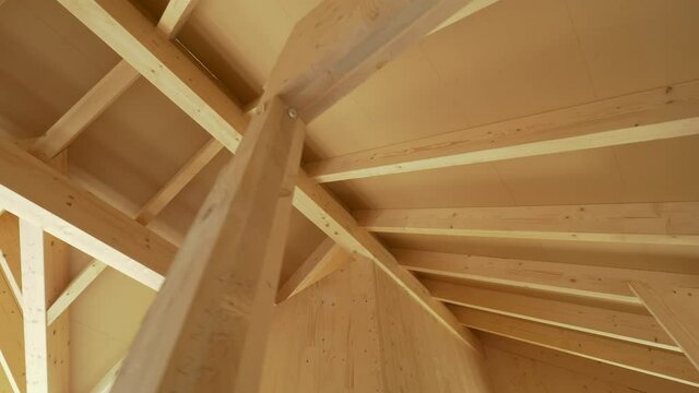 Beautiful view of the massive ceiling beams of a modern cross laminated timber house. Gorgeous hardwood structure of the ceiling of a contemporary glue laminated housing project under construction.