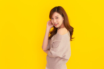 Beautiful Asian young woman's portrait on bright yellow background