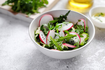 Fresh green spring salad with arugula and radish at light background