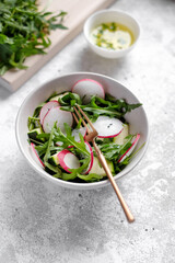 Fresh green spring salad with arugula and radish at light background