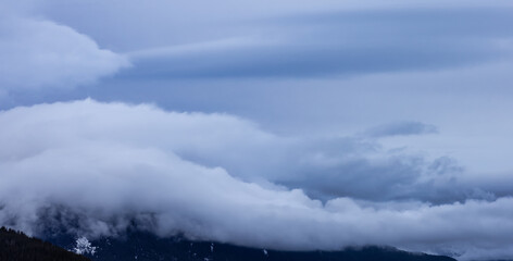 Panoramic View of Puffy Clouds over the Canadian Mountain Landscape. Colorful Winter Sunset Cloudscape Background. Taken between Squamish and Whistler, British Columbia, Canada.